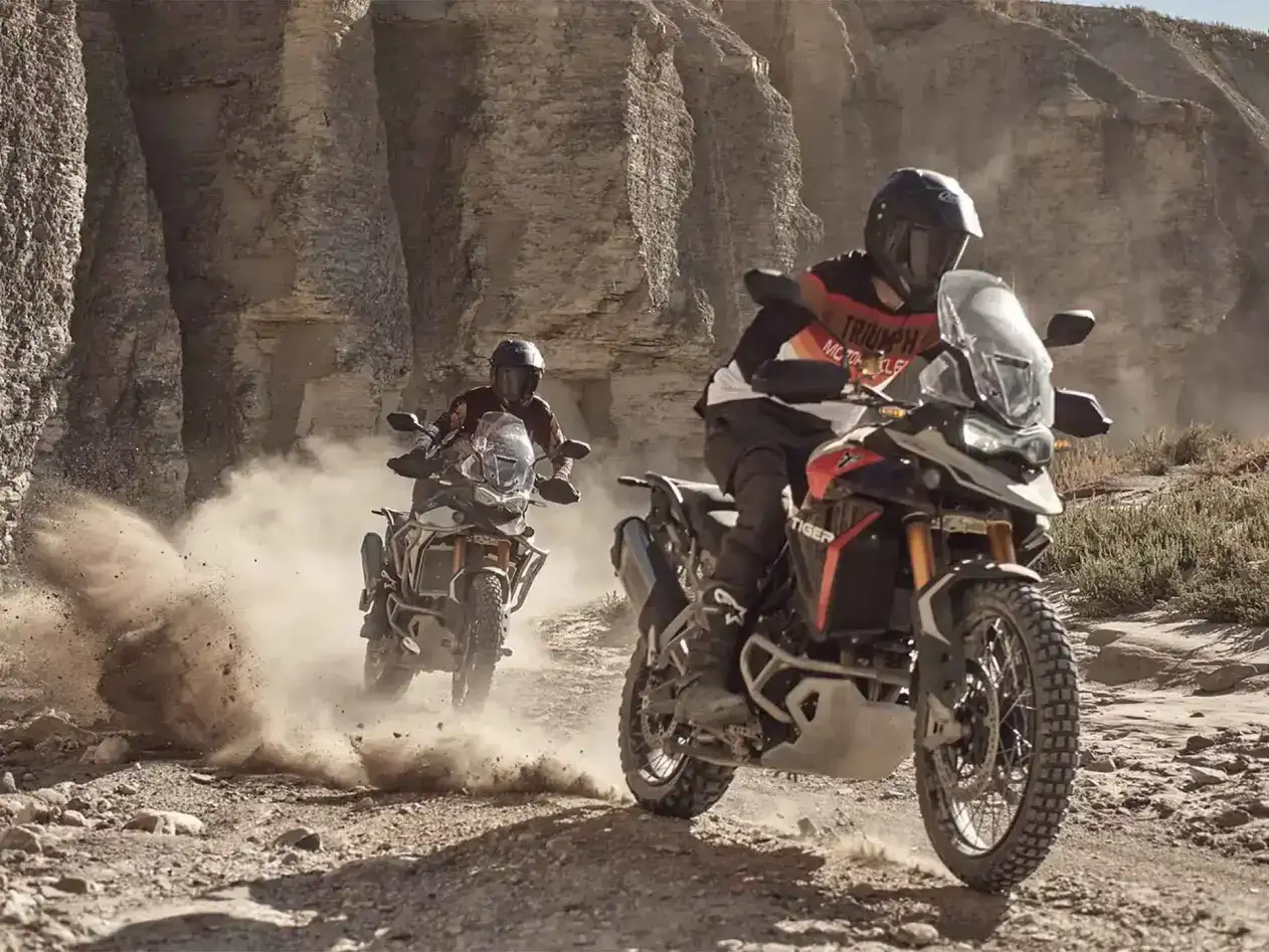 Two motorcycles riding on dusty terrain