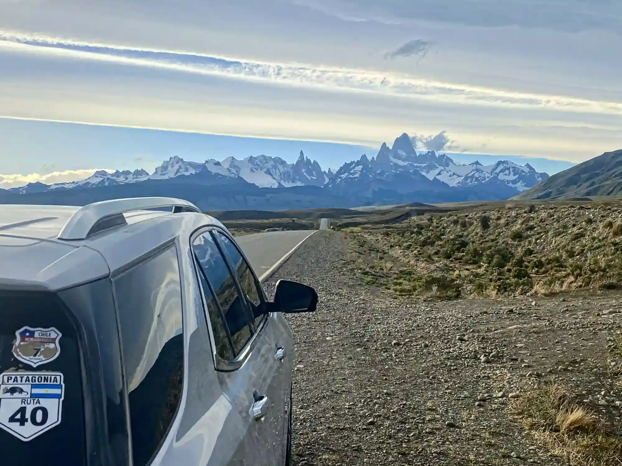 A support vehicle with a Patagonia Ruta 40 sticker parked beside the road approaching the Fitz Roy and Cerro Torre range near El Chaltén.